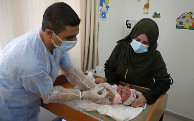Un employé de l'UNRWA vaccine des enfants contre la polio et le rotavirus dans une clinique du camp de réfugiés de Bureij, au centre de la bande de Gaza, le 9 septembre 2020. (Mohammed ABED / AFP)