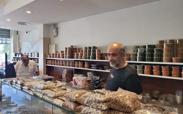 Haim Mergashvili parle à un journaliste dans son magasin de Haïfa, le 4 août 2024. (Crédit : Canaan Lidor/Times of Israel)