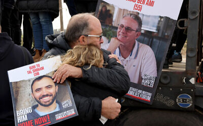 Des proches des otages détenus par les terroristes du Hamas avec des photos d'Ohad Ben Ami, 55 ans, et de Tal Shoham, 38 ans, se tiennent le long de la clôture frontalière de Gaza, au kibboutz Nirim, avec des hauts-parleurs montés sur une grue pour tenter de transmettre un message d'espoir aux captifs qui viennent de passer presque cent jours en détention, le 11 janvier 2024. (Crédit : Jack Guez / AFP)