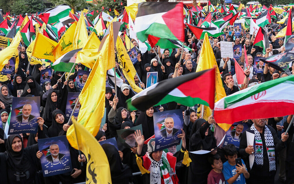 Des Iraniens brandissant des drapeaux palestiniens et des portraits du chef terroriste du Hamas, Ismaïl Haniyeh (au centre), lors d'une manifestation dénonçant son assassinat, sur la place de Palestine, dans la capitale Téhéran, le 31 juillet 2024. (Crédit : AFP)