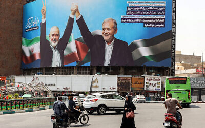 Une femme marchant au milieu de véhicules à côté d'un panneau d'affichage du président iranien Massoud Pezeshkian (à droite) et du défunt chef politique du groupe terroriste palestinien du Hamas Ismaïl Haniyeh sur la place de la Valise à Téhéran, le 1er août 2024. (Crédit : AFP)