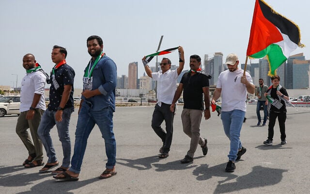 Un homme tenant un drapeau palestinien marchant avec d'autres vers la mosquée Imam Mohammed ben Abdul Wahhab à Doha pour faire ses adieux au chef du Hamas Ismaïl Haniyeh après son assassinat à Téhéran dans un attentat imputé à Israël, le 2 août 2024. (Crédit : Karim Jaafar/AFP)