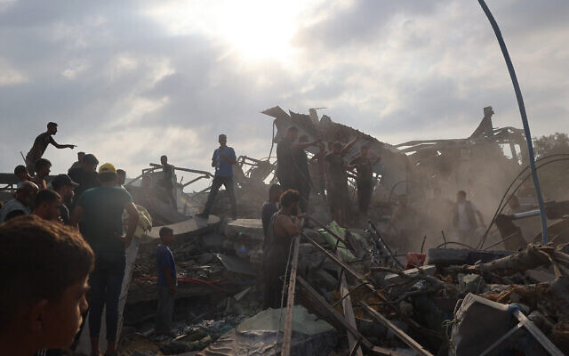 Des Palestiniens inspectant le site d'une frappe israélienne, à al-Zawayda, dans le centre de la bande de Gaza, le 17 août 2024. (Crédit : Eyad Baba/AFP)