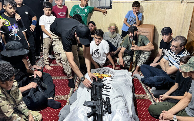 Un combattant place un fusil sur le corps de Khalil Maqdah, un haut responsable de la branche armée du Fatah, tué dans une frappe israélienne près de la ville de Sidon, dans le sud du Liban, avant ses funérailles dans le camp de réfugiés palestiniens d'Ain al-Helweh, le 21 août 2024. (Crédit : Mahmoud ZAYYAT / AFP) Un combattant place un fusil sur le corps de Khalil Maqdah, un haut responsable de la branche armée du Fatah, tué dans une frappe israélienne près de la ville de Sidon, dans le sud du Liban, avant ses funérailles dans le camp de réfugiés palestiniens d'Ain al-Helweh, le 21 août 2024. (Crédit : Mahmoud ZAYYAT / AFP)