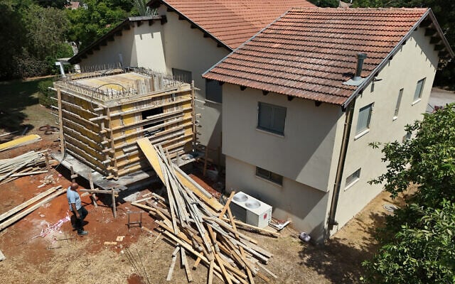 Une vue aérienne montrant un ouvrier construisant un abri anti-atomique à côté de la maison d'un couple israélien, à Tel Mond, dans le centre d'Israël, le 22 août 2024. (Crédit : Jack Guez/AFP) Une vue aérienne montrant un ouvrier construisant un abri anti-atomique à côté de la maison d'un couple israélien, à Tel Mond, dans le centre d'Israël, le 22 août 2024. (Crédit : Jack Guez/AFP)