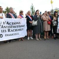 Des manifestants et des élus locaux tenant une banderole lors d'une manifestation contre le racisme et l'antisémitisme, au lendemain de l'attaque d'une synagogue dans la station balnéaire de La Grand Motte, à Paris, le 25 août 2024. (Crédit : Alain Jocard/AFP)
