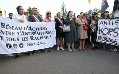 Des manifestants et des élus locaux tenant une banderole lors d'une manifestation contre le racisme et l'antisémitisme, au lendemain de l'attaque d'une synagogue dans la station balnéaire de La Grand Motte, à Paris, le 25 août 2024. (Crédit : Alain Jocard/AFP)