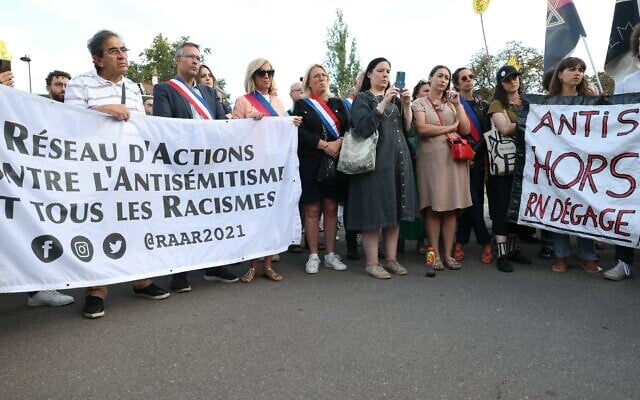 Des manifestants et des élus locaux tenant une banderole lors d'une manifestation contre le racisme et l'antisémitisme, au lendemain de l'attaque d'une synagogue dans la station balnéaire de La Grand Motte, à Paris, le 25 août 2024. (Crédit : Alain Jocard/AFP)
