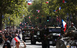 Des reconstituants vêtus d'uniformes de guerre défilent sur des véhicules militaires du temps de la guerre lors d'une reconstitution marquant le 80e anniversaire de la libération de Paris des Allemands pendant la Seconde Guerre mondiale, à Paris, le 25 août 2024. (Crédit : ALAIN JOCARD / AFP)