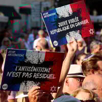 Des personnes portant des pancartes avec le logo du collectif « Nous Vivrons », où l'on peut lire « L'antisémitisme n'est pas résiduel » et « Juive violée, la République est en danger » participent à une manifestation contre l'antisémitisme à l'appel du Conseil représentatif des institutions juives de France (Crif) sur la place de la Comédie à Montpellier, le 27 août 2024, suite à l'incendie et à l'explosion de voitures qui ont visé une synagogue de La Grande-Motte, le 24 août 2024. (Crédit : Pascal GUYOT / AFP)