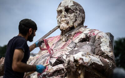 Le sculpteur syrien en exil Khaled Dawwa détruisant son œuvre d'art géante "Le roi des trous", représentant un potentat au corps massif, pour organiser une protestation à l'occasion de la Journée internationale des disparus, devant les bureaux des Nations unies, à Genève, le 30 août 2024.(Crédit : Fabrice Coffrini/AFP)