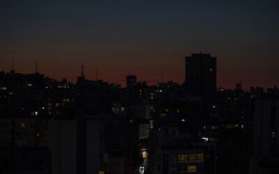 La capitale Beyrouth dans l'obscurité au cours d'une panne d'électricité, au couché du soleil se couche, au Liban, le 29 mars 2021. (Crédit : Hassan Ammar/AP)