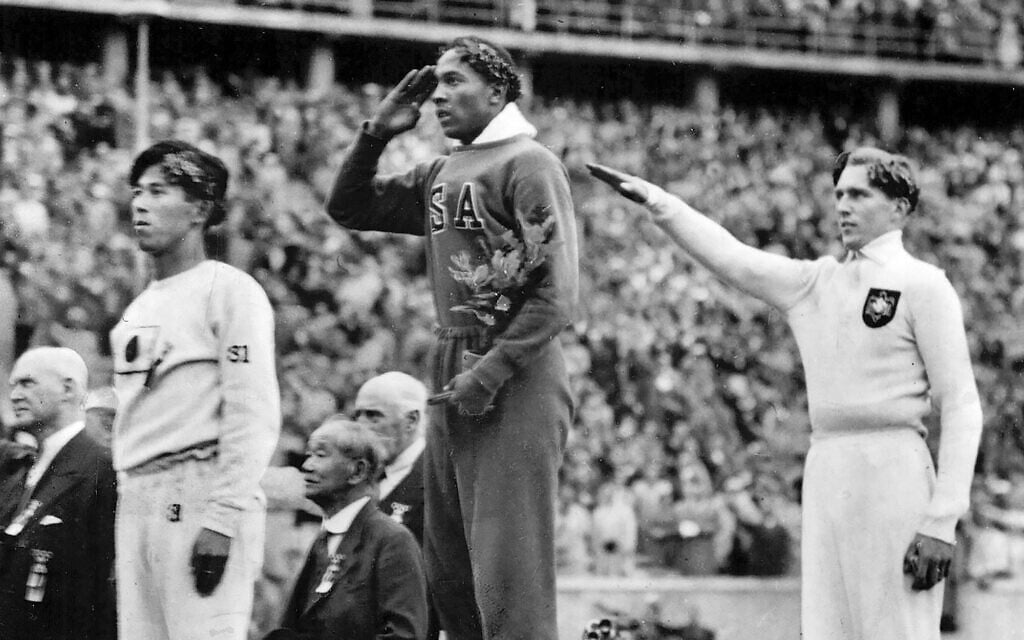 De gauche à droite sur le podium : le médaillé de bronze Jajima, du Japon, le médaillé d’or Jesse Owens, des États-Unis, et le médaillé d’argent, Lutz Long, d’Allemagne, lors des Jeux olympiques d'été de 1936, à Berlin, le 11 août 1936. (Crédit : AP) De gauche à droite sur le podium : le médaillé de bronze Jajima, du Japon, le médaillé d’or Jesse Owens, des États-Unis, et le médaillé d’argent, Lutz Long, d’Allemagne, lors des Jeux olympiques d'été de 1936, à Berlin, le 11 août 1936. (Crédit : AP)
