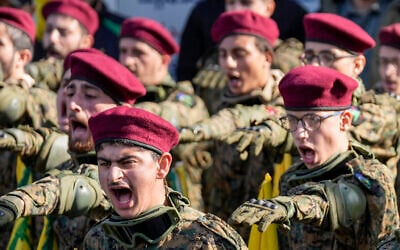 Des combattants du Hezbollah scandent des slogans lors de la procession funéraire d'un commandant du groupe terroriste, Wissam Tawil, lors de son inhumation dans le village de Khirbet Selm, dans le sud du Liban, le 9 janvier 2024. (Crédit : AP Photo/Hussein Malla)