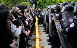 Des manifestants pro-palestiniens et anti-israéliens scandent des slogans devant les policiers de l'Université de Chicago alors qu'ils sont tenus à l'écart du centre du campus, le temps de démanteler le campement étudiant, le 7 mai 2024, à Chicago. (AP/Charles Rex Arbogast)