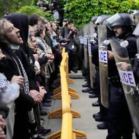 Des manifestants pro-palestiniens et anti-israéliens scandent des slogans devant les policiers de l'Université de Chicago alors qu'ils sont tenus à l'écart du centre du campus, le temps de démanteler le campement étudiant, le 7 mai 2024, à Chicago. (AP/Charles Rex Arbogast)