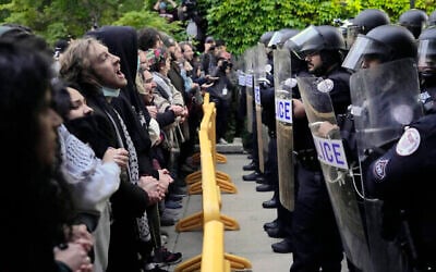 Des manifestants pro-palestiniens et anti-israéliens scandent des slogans devant les policiers de l'Université de Chicago alors qu'ils sont tenus à l'écart du centre du campus, le temps de démanteler le campement étudiant, le 7 mai 2024, à Chicago. (AP/Charles Rex Arbogast)