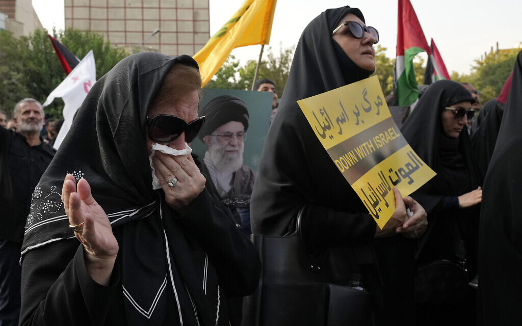 Un manifestante pleurant tandis que les autres tiennent une pancarte anti-israélienne et une affiche du guide suprême iranien, l'ayatollah Ali Khamenei, lors d'une manifestation visant à condamner l'assassinat du chef du Hamas, Ismaïl Haniyeh, sur la place Felestin (Palestine), à Téhéran, en Iran, le 31 juillet 2024. (Crédit : Vahid Salemi/AP)