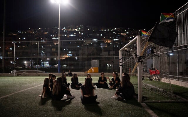 Des jeunes assis à côté d'une lucarne en mémoire de douze enfants et adolescents tués lors d'un tir de roquette du Hezbollah sur un terrain de football dans la ville de Majdal Shams, sur le plateau du Golan, le 1er août 2024. (Crédit : Leo Correa/AP)