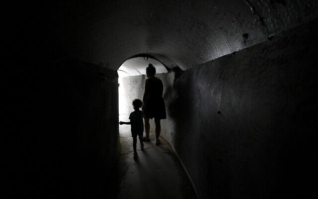 Une femme et un enfant traversent une réplique d'un tunnel utilisé par les terroristes du Hamas dans la bande de Gaza, avant la manifestation hebdomadaire des familles d'otages pour exiger leur libération, à Tel Aviv, le 17 août 2024. (Crédit : Tsafrir Abayov/AP)