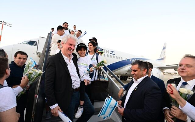 L'Évêque Paul Francis Lanier, président du conseil d'administration de l'IFCJ (Communauté internationale des chrétiens et des juifs), tenant un jeune oleh hadash à son arrivée en Israël et est accueilli par le ministre de l'Alyah et de l'Intégration Ofir Sofer, le 1er août 2024. (Crédit : Yossi Zeliger)