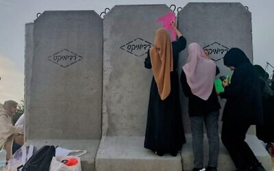 Des bénévoles bédouins peignent un abri anti-roquettes en béton installé la veille dans le village bédouin non reconnu d'Umm al-Khiran, dans le sud d'Israël, le 7 décembre 2023 (Crédit : Gianluca Pacchiani / Times of Israel)