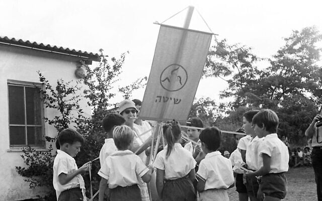 Des enfants entrant en CP tenant leur drapeau, qui porte le nom d'Acacia, au kibboutz Beeri, dans le sud d'Israël. (Crédit :  Archives du kibbutz Beeri)