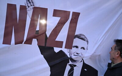 Un manifestant regarde une bannière représentant le leader régional de Thuringe du parti d'extrême-droite Alternative pour l'Allemagne (AfD), Björn Höcke, lors d'une manifestation contre le racisme et la politique d'extrême-droite, le 5 février 2024, à Francfort-sur-le-Main. (Photo de Kirill KUDRYAVTSEV / AFP)