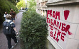 Illustration : Des graffitis "De la rivière à la mer" sur un bâtiment adjacent à un campement protestant contre les liens de l'université de Washington avec Israël et Boeing sur le campus universitaire, à Seattle (Etat de Washington), le 12 mai 2024. (Crédit : Jason Redmond/AFP)