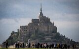 Des visiteurs quittent les lieux après avoir assisté au relais de la flamme olympique au Mont-Saint-Michel, dans le nord-ouest de la France, le 31 mai 2024, avant les Jeux olympiques et paralympiques de Paris 2024. (Photo MIGUEL MEDINA / AFP)