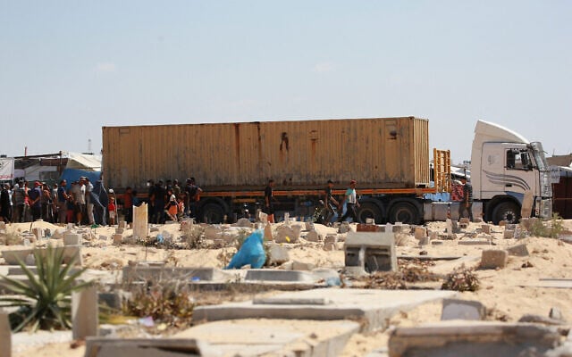 Des personnes entourant un conteneur transportant des corps de Palestiniens qui ont été arrêtés puis relâchés par Israël, avant des funérailles collectives dans un cimetière, à Khan Younès, dans le sud de la bande de Gaza, le 5 août 2024. (Crédit : Bashar Taleb/AFP) Des personnes entourant un conteneur transportant des corps de Palestiniens qui ont été arrêtés puis relâchés par Israël, avant des funérailles collectives dans un cimetière, à Khan Younès, dans le sud de la bande de Gaza, le 5 août 2024. (Crédit : Bashar Taleb/AFP)