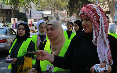 Des délégués électoraux distribuent des cartes à l'extérieur d'un bureau de vote à al-Salt, près de la capitale Amman, le 10 septembre 2024. (Crédit : Khalil MAZRAAWI / AFP)