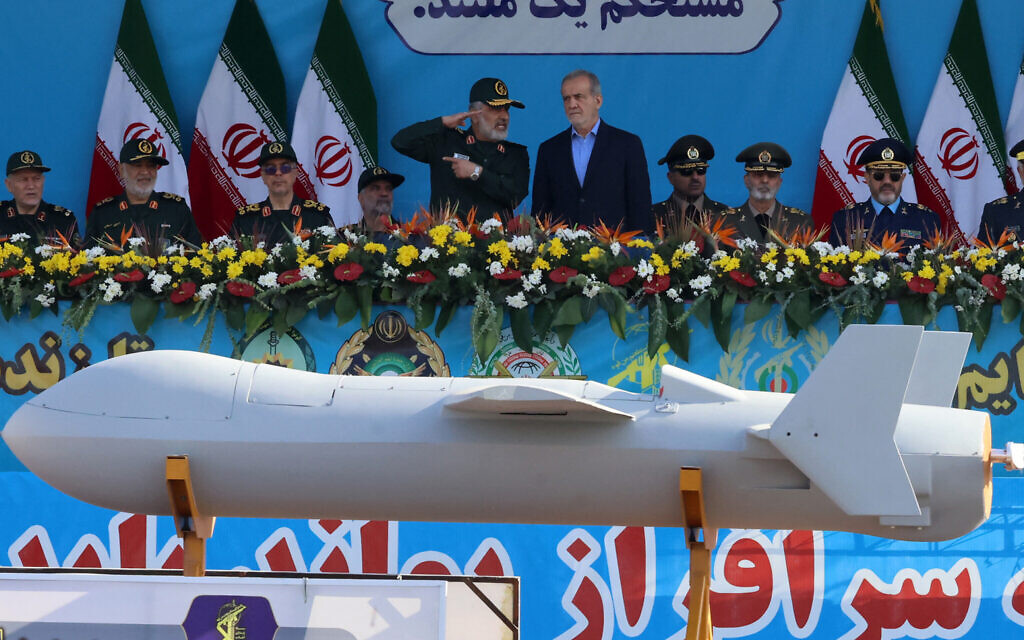Le président iranien Massoud Pezeshkian (à droite) et le commandant des forces aérospatiales du du Corps des Gardiens de la Révolution islamique (CGRI), le bras armé de l'Iran, Amir Ali Hajizadeh regardant le nouveau drone iranien Shahed 136-B lors d'une parade militaire annuelle marquant l'anniversaire du déclenchement de la guerre de 1980-1988 contre l'Irak de Saddam Hussein, à Téhéran, le 21 septembre 2024. (Crédit : Atta Kenare/AFP)