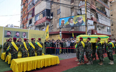 Des membres du Hezbollah autour des cercueils de terroristes tués lors d'une frappe israélienne la veille, lors de leurs funérailles dans la banlieue sud de Beyrouth, le 21 septembre 2024. (Crédit : ANWAR AMRO / AFP)