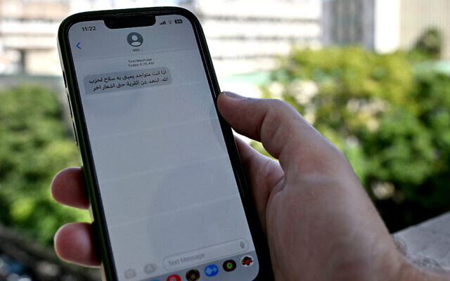Un Libanais consulte un message reçu sur son téléphone portable à Beyrouth le 23 septembre 2024, appelant les civils à évacuer les zones où le Hezbollah cache ses armes. (Crédit : JOSEPH EID / AFP)