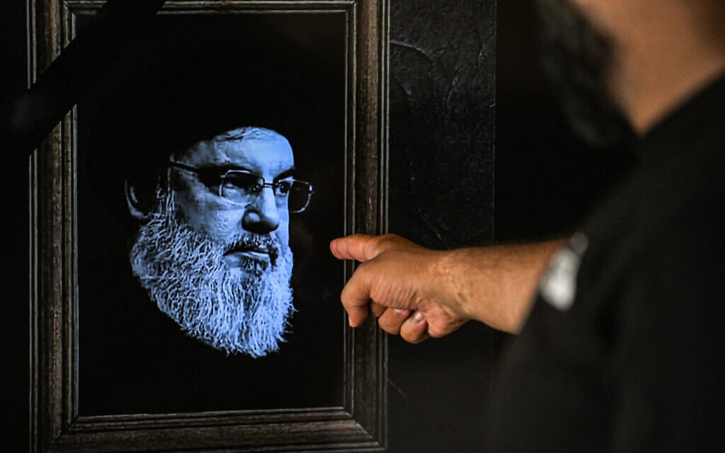 Un homme montrant un téléviseur affichant une image du chef du Hezbollah Hassan Nasrallah, avec une bande noire en signe de deuil, lors d'une émission de la chaîne de télévision libanaise NBN, à Beyrouth, le 28 septembre 2024. (Crédit : Joseph Eid/AFP) Un homme montrant un téléviseur affichant une image du chef du Hezbollah Hassan Nasrallah, avec une bande noire en signe de deuil, lors d'une émission de la chaîne de télévision libanaise NBN, à Beyrouth, le 28 septembre 2024. (Crédit : Joseph Eid/AFP)
