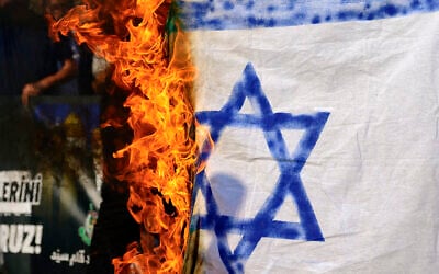 Des manifestants brûlant un drapeau d'Israël improvisé lors d'un rassemblement de protestation contre l’élimination du chef du Hezbollah, Hassan Nasrallah, devant le consulat d'Israël à Istanbul, le 29 septembre 2024. (Crédit : Yasin Akgul/AFP)
