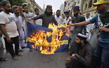 Des partisans du parti islamiste radical "Tehreek-e-Labaik Pakistan" brûlent une représentation du drapeau suédois lors d'un rassemblement visant à dénoncer l'incendie du Coran, à Karachi, au Pakistan, le 7 juillet 2023. (Crédit : AP/Fareed Khan)
