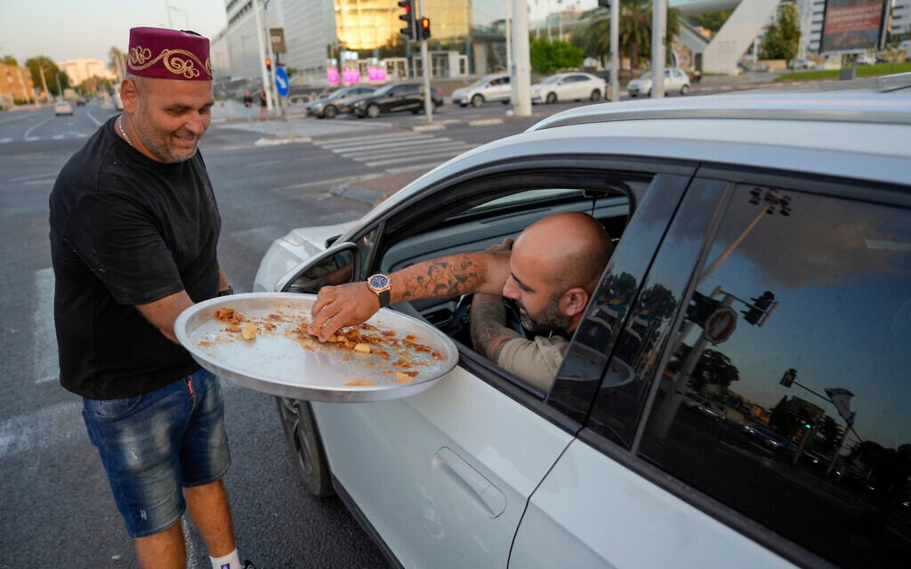 Un Israélien, Avi Azran, distribue des bonbons pour fêter la nouvelle de la mort du chef du Hezbollah Hassan Nasrallah dans la ville de Nahariya, dans le nord d'Israël, samedi 28 septembre 2024. (Crédit : AP/Baz Ratner)