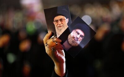 Un partisan du Hezbollah brandit des portraits du chef du Hezbollah,  Hassan Nasrallah, à droite, et du guide suprême iranien, l'ayatollah Ali Khamenei, au neuvième jour de l'Achoura, un rituel de dix jours commémorant la mort de l'imam Hussein, dans la banlieue sud de Beyrouth, au Liban, le 19 septembre 2018. (Crédit : AP Photo/Hussein Malla)