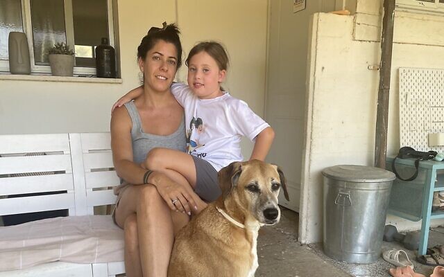 Noam Mash avec sa fille Dar et la chienne de la famille, Belle, sur le porche de leur maison temporaire du kibboutz Re'im, près de la frontière avec Gaza, le 1er septembre 2024. (Crédit : Sue Surkes/Times of Israel)
•