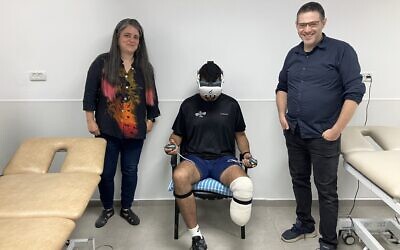 Miri Berger, à gauche, et Aryeh Katz, à droite, cofondateurs de 6Degrees, font don de leur jeu de réalité virtuelle MyMove à Tamir, un soldat récemment blessé lors des combats dans la bande de Gaza, au centre hospitalier Sheba, le 28 août 2024. (Crédit : Diana Bletter/Times of Israel)
