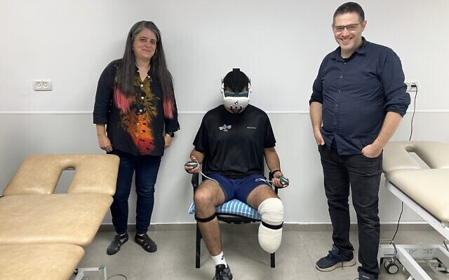 Miri Berger, à gauche, et Aryeh Katz, à droite, cofondateurs de 6Degrees, font don de leur jeu de réalité virtuelle MyMove à Tamir, un soldat récemment blessé lors des combats dans la bande de Gaza, au centre hospitalier Sheba, le 28 août 2024. (Crédit : Diana Bletter/Times of Israel)