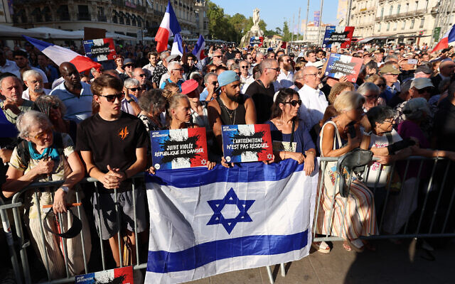 Des participants portant des pancartes « Juive violée, République en danger » et « L'antisémitisme n'est pas résiduel », avec des drapeaux français et un drapeau israélien, participent à une manifestation contre l'antisémitisme appelée par le Conseil représentatif des institutions juives de France (CRIF) sur la place de la Comédie à Montpellier, dans le sud de la France, le 27 août 2024. (Crédit : Pascal Guyot/AFP) Des participants portant des pancartes « Juive violée, République en danger » et « L'antisémitisme n'est pas résiduel », avec des drapeaux français et un drapeau israélien, participent à une manifestation contre l'antisémitisme appelée par le Conseil représentatif des institutions juives de France (CRIF) sur la place de la Comédie à Montpellier, dans le sud de la France, le 27 août 2024. (Crédit : Pascal Guyot/AFP)