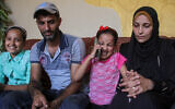 Asmaa Abu Sakran et son époux Khaled Abu Sakran, séparés de leur fils Maher depuis octobre 2023, après qu'il a fui le nord de Gaza avec ses grands-parents sur ordre de l'armée israélienne, assis à côté de leurs autres enfants alors qu'ils ont une conversation téléphonique avec Maher, dans la ville de Gaza, le 19 septembre 2024. (Crédit : Mahmoud Issa/AP)