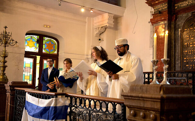 Le rabbin d'Ec Chajim David Maxa et une femme rabbin en cours de formation, Klára Kopytková, dirigent la prière de Kol Nidrei pendant l'office  de Yom Kippour à la synagogue Klausen à Prague tandis que la présidente d'Ec Chajim, Anna Noskova, tient la Torah avec le vice-président de l'Union mondiale du judaïsme progressiste, Andrew Keene, le 11 octobre 2024. (Crédit : Dana Cabanova ; Autorisation : Musée juif de Prague)