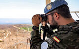 Un Casque bleu du contingent espagnol regardant à travers des jumelles depuis un belvédère de la caserne de la Force intérimaire des Nations unies au Liban (FINUL), près de Khiam, dans le sud du Liban, le 23 août 2024. (Crédit : Anwar Amro/AFP)