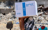 Photo d'illustration : Un homme portant un paquet d'aide humanitaire fourni par l'Office de secours et de travaux des Nations unies pour les réfugiés de Palestine (UNRWA), dans le centre de la ville de Gaza, le 27 août 2024. (Crédit : Omar Al-Qattaa/AFP)