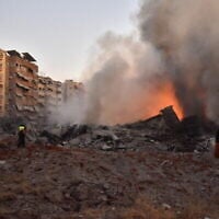 Des riverains regardant l'incendie qui fait rage au milieu des décombres d'un bâtiment détruit lors d'une frappe aérienne israélienne visant le principal quartier général du Hezbollah, dans la banlieue sud de Beyrouth, le 27 septembre 2024. (Crédit : Fadel Itani/AFP)