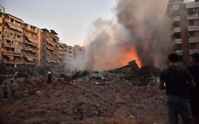 Des riverains regardant l'incendie qui fait rage au milieu des décombres d'un bâtiment détruit lors d'une frappe aérienne israélienne visant le principal quartier général du Hezbollah, dans la banlieue sud de Beyrouth, le 27 septembre 2024. (Crédit : Fadel Itani/AFP)